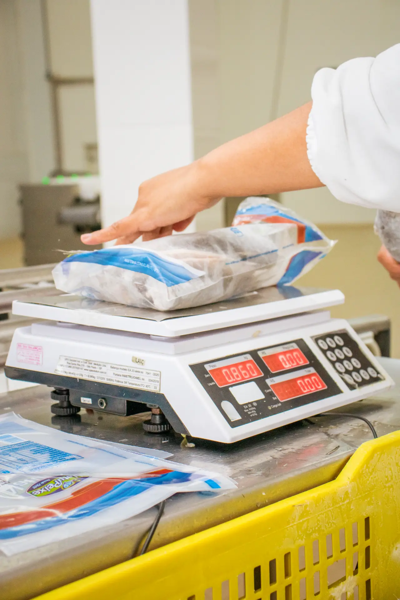 Balança pesando embalagem de pescado congelado em linha de processamento